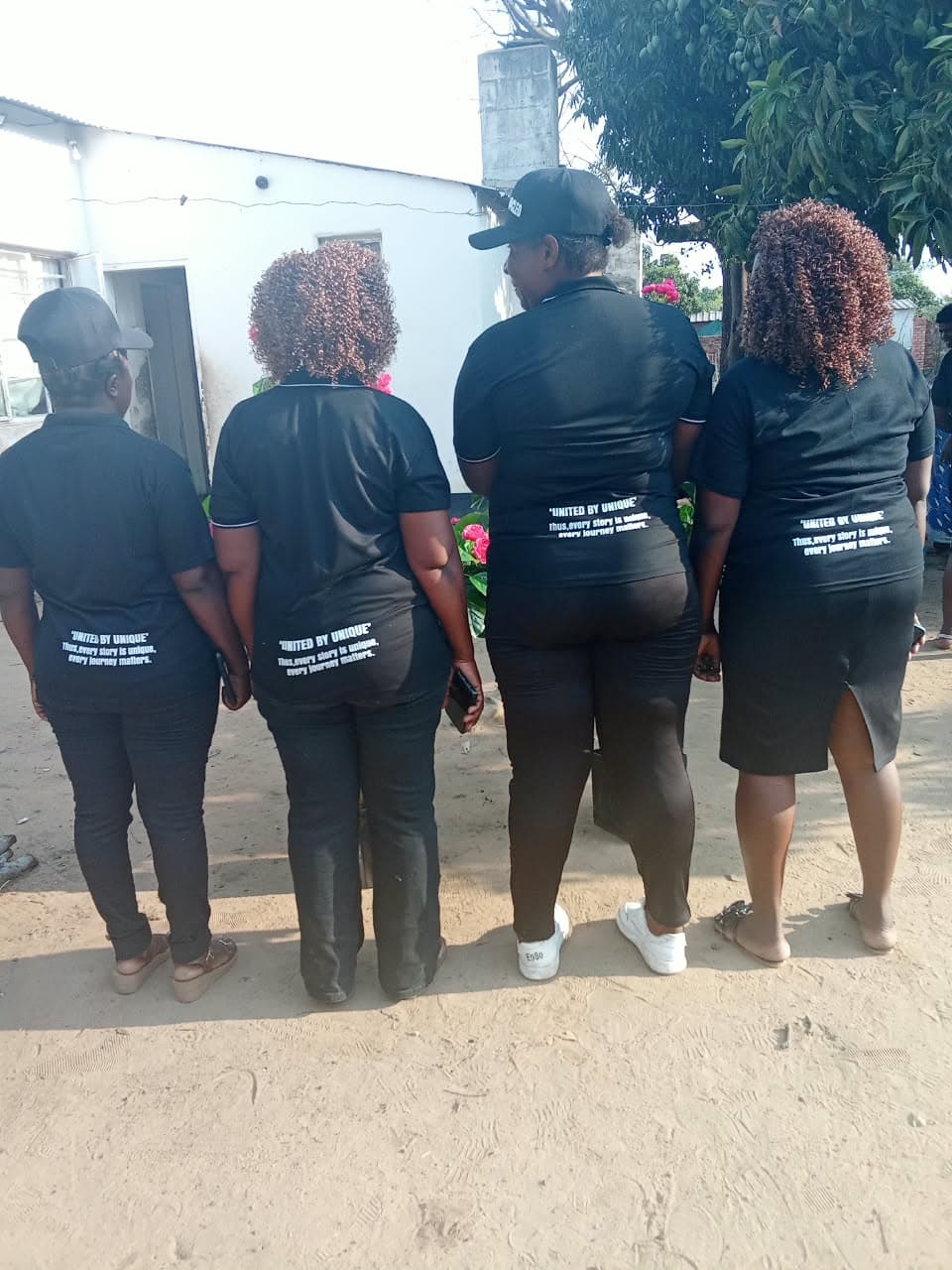Four women showing the messages on the backs of their awareness shirts