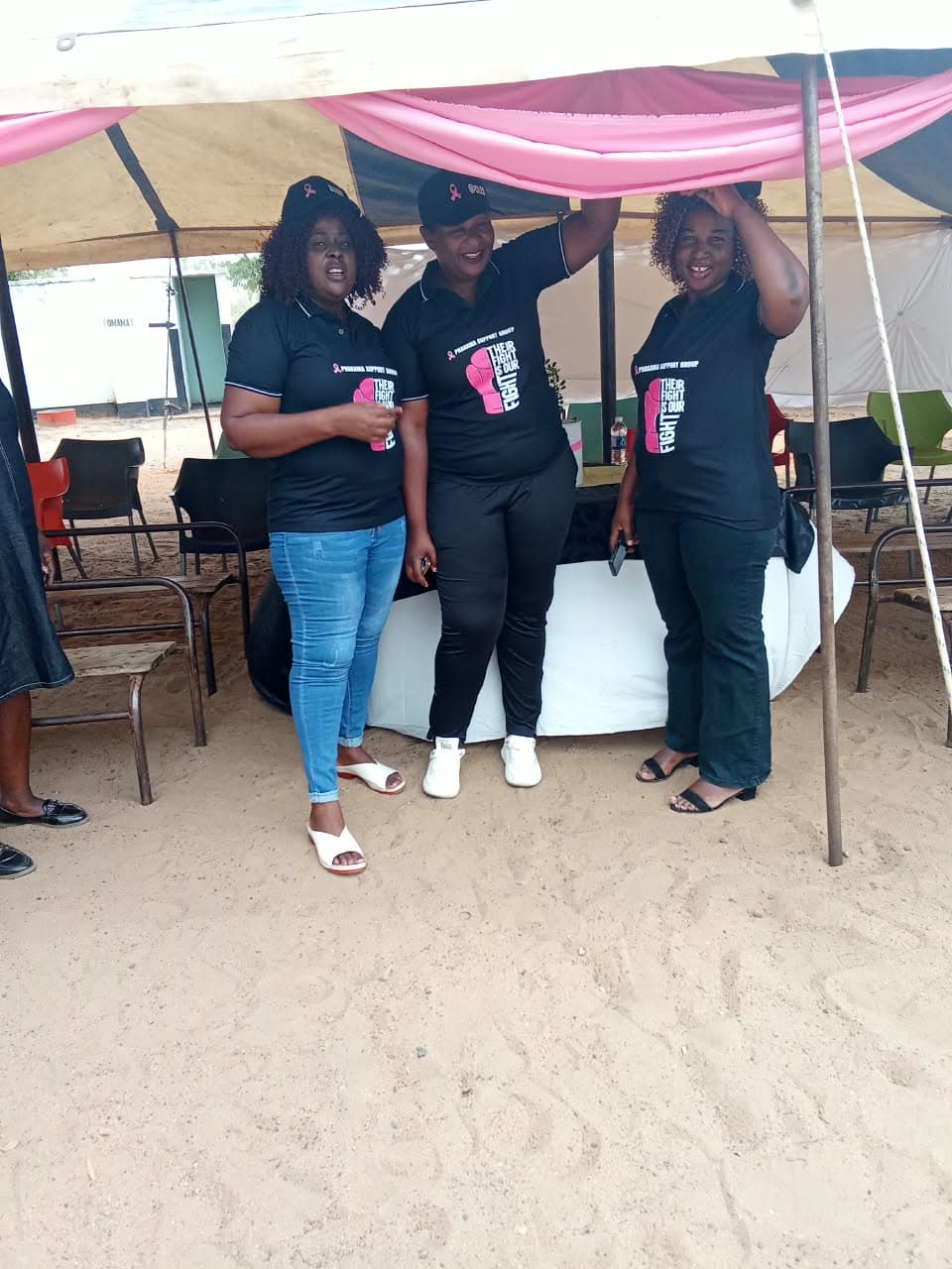 Women wearing breast cancer awareness shirts beneath a canopy